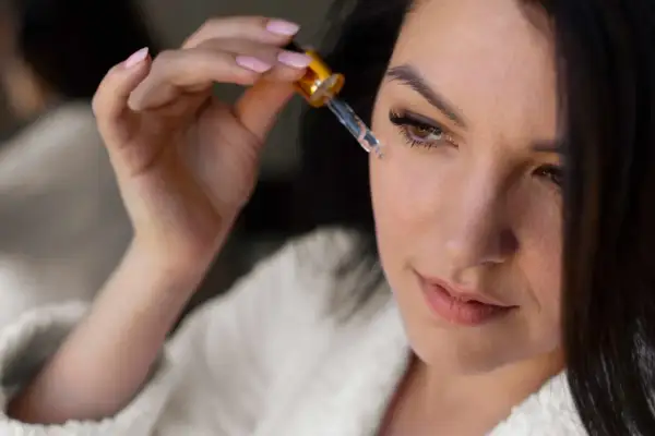 Kobieta aplikuje serum na twarz za pomocą pipety.